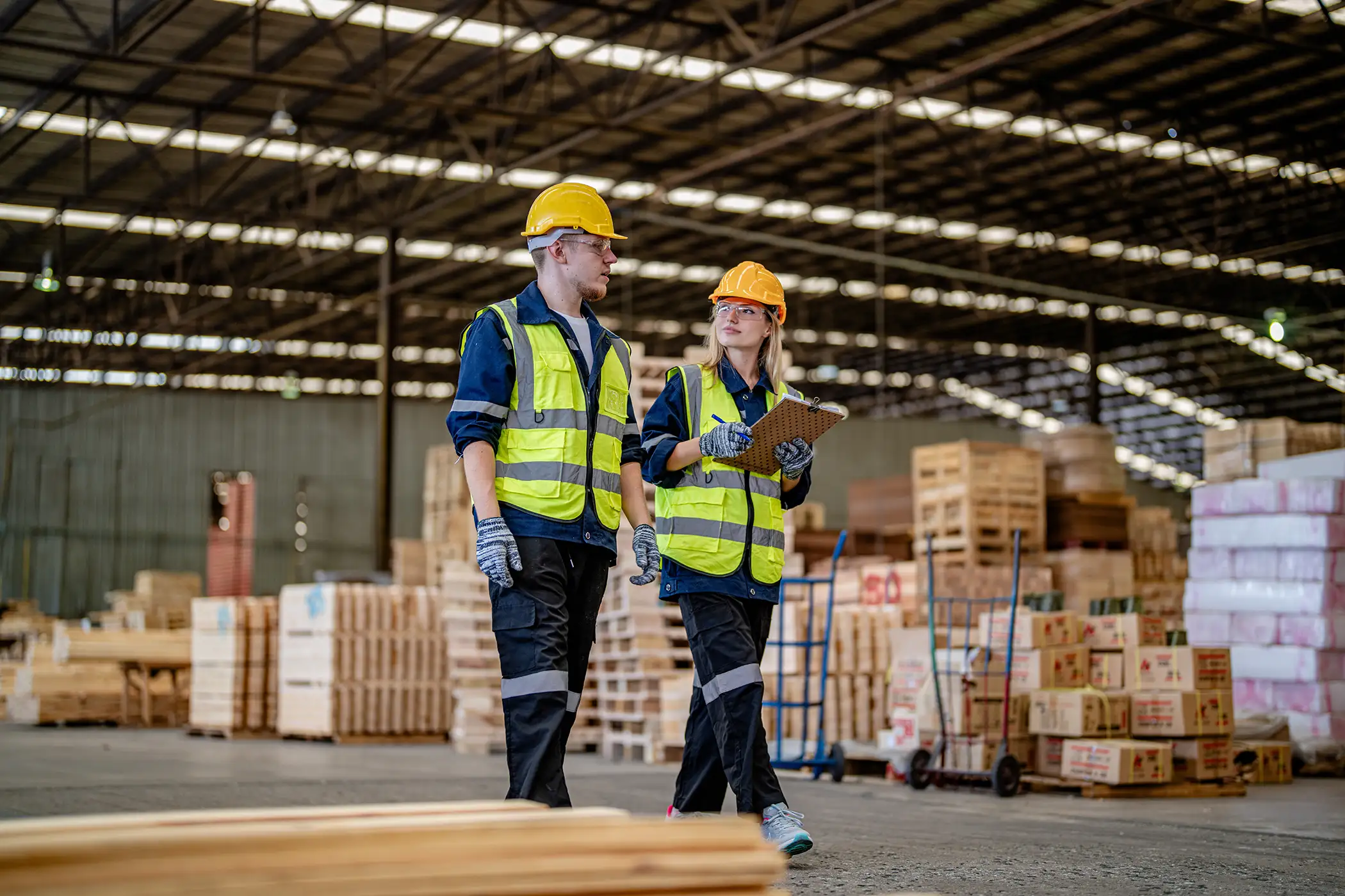 Two employees with hard hats walking through a warehouse